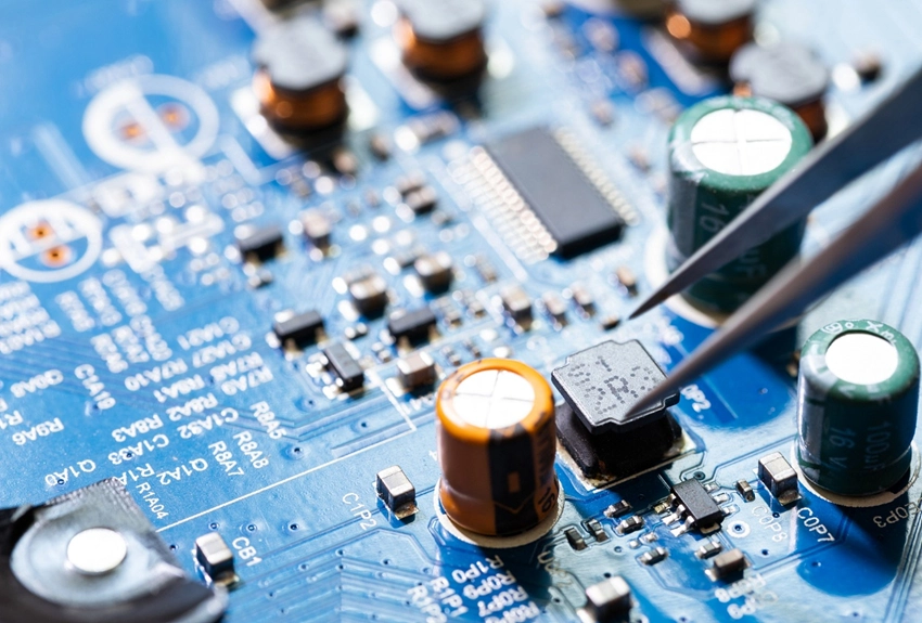 Close-up of SMT PCB assembly and inspection with tweezers on a blue circuit board